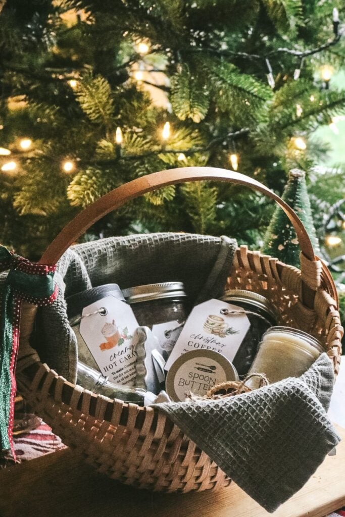 basket full of homemade christmas gifts in front of a christmas tree.