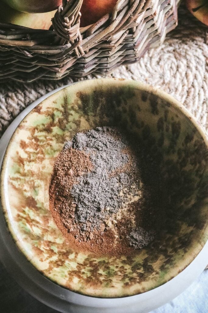overhead view of an antique spongeware bowl with the spices for homemade apple pie spice.