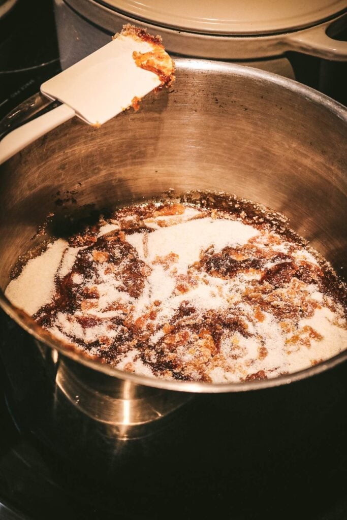 homemade dry caramel halfway through melting with clumps of white sugar and caramel.