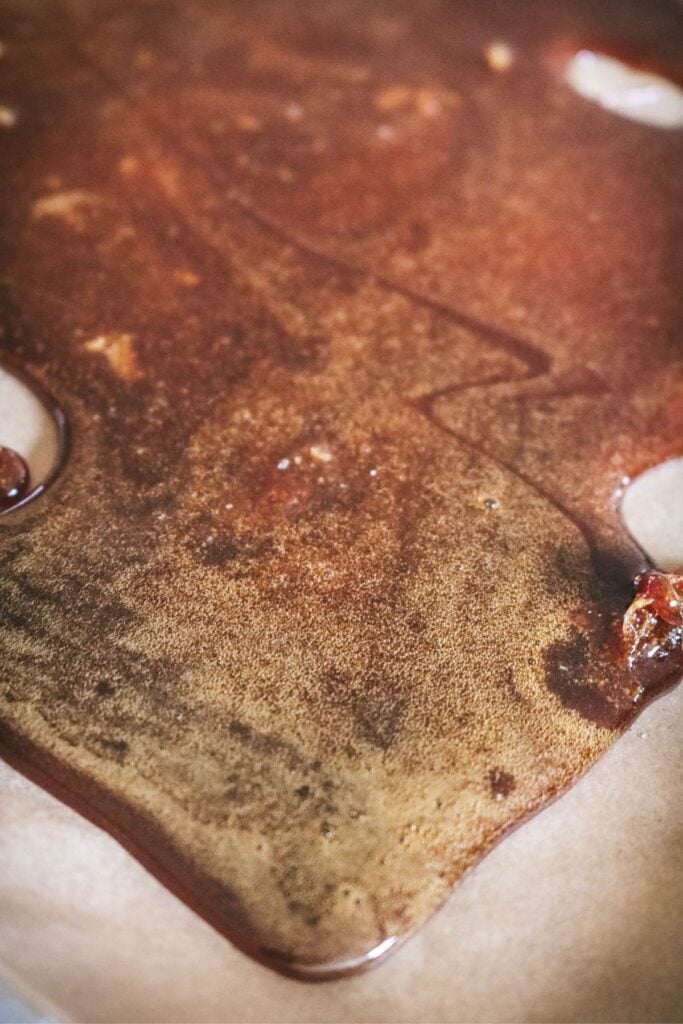 dry caramel poured onto a half sheet pan lined with parchment paper to make caramel sugar.