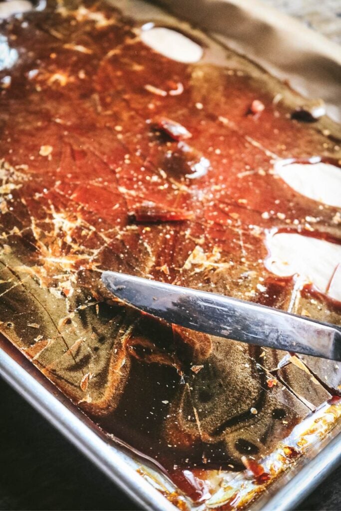 shattering hard caramel with a butter knife to make caramel sugar.