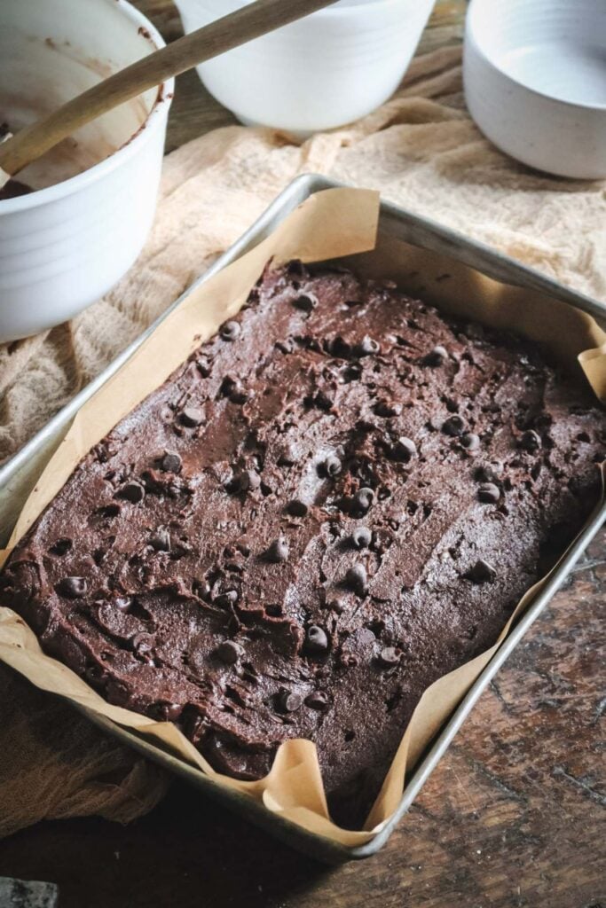 chocolate chocolate chip cookie bars in a lined baking pan before baking.