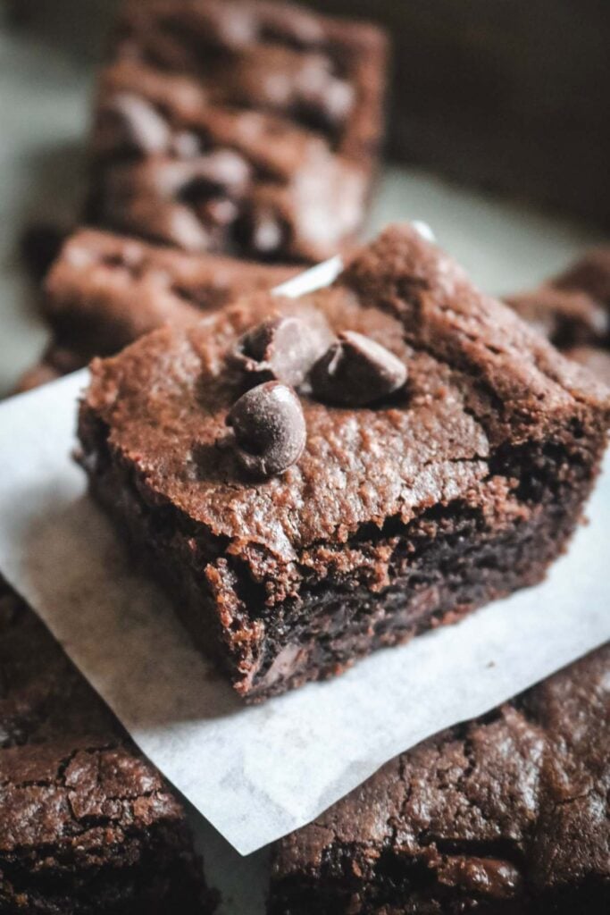 double chocolate cookie bars on a piece of parchment with extra chocolate chips on the side.