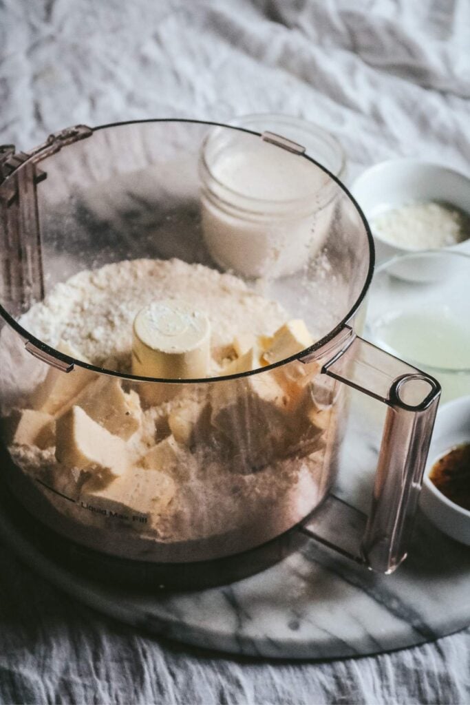 food processor with flour, sugar, baking powder, salt, and butter to make vanilla bean scones.