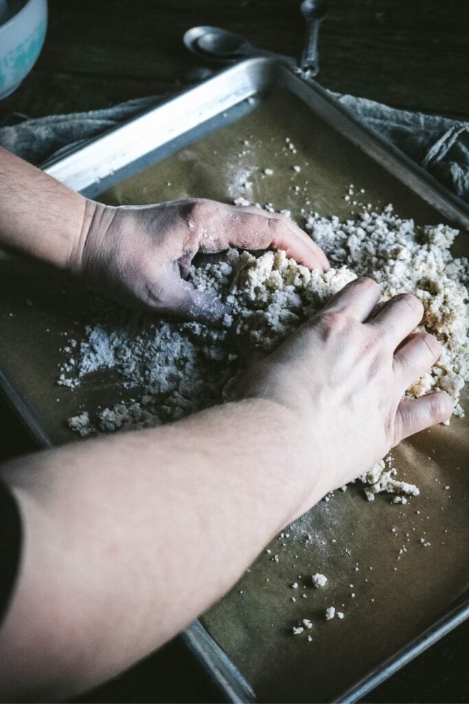 kneading scone dough into a ball on a baking sheet.
