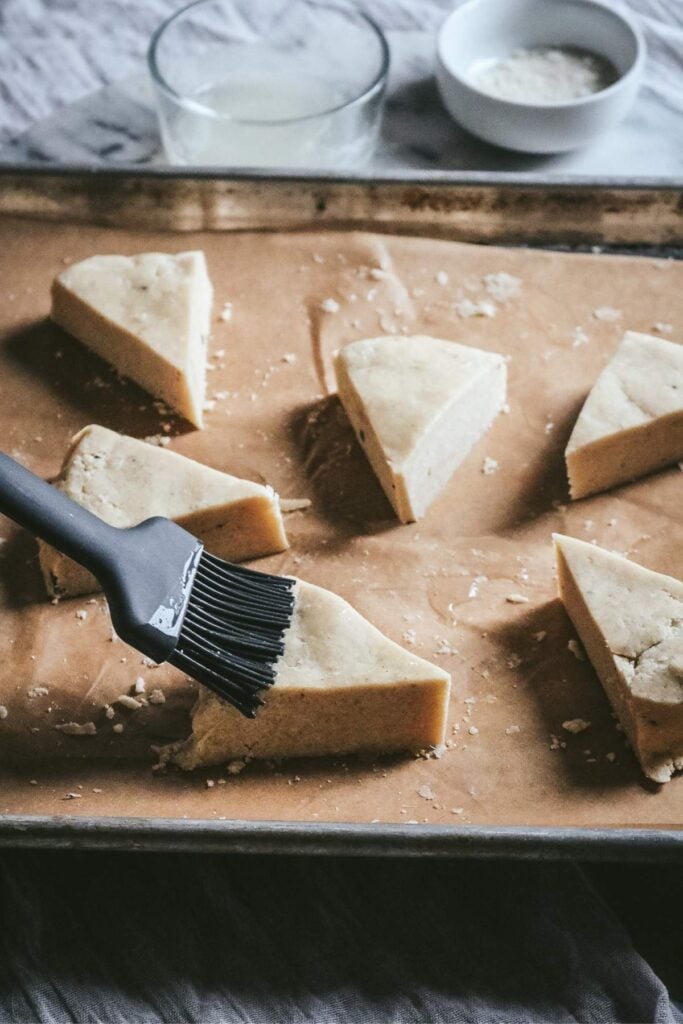 brushing unbaked vanilla bean scones with egg white before baking.