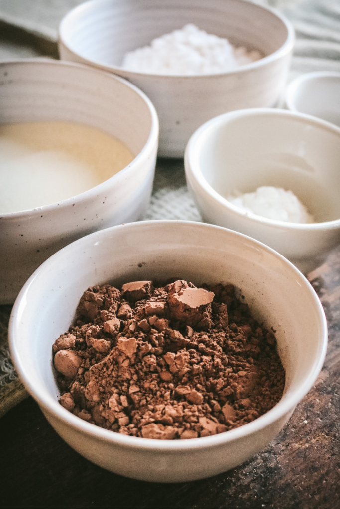 close up view of ingredients to make hot chocolate in a jar like cocoa powder and powdered milk.