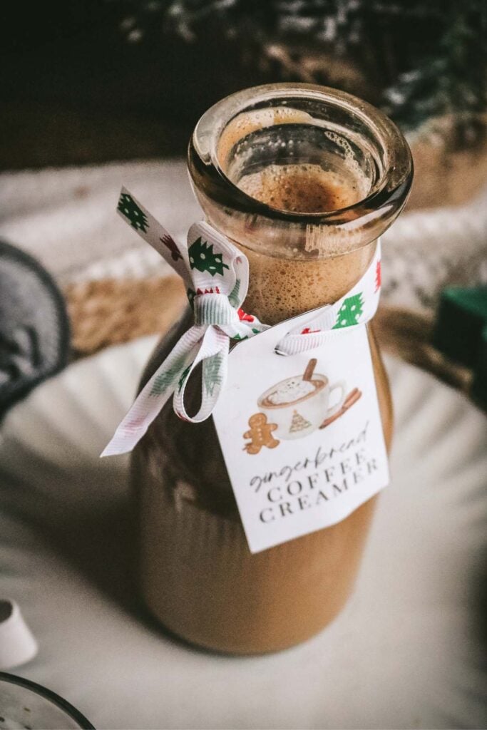 a glass bottle with homemade gingerbread creamer for coffee with a printable tag attached with ribbon.