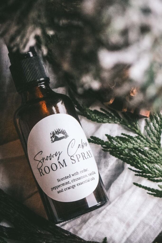 amber glass bottle that reads snowy cabin room spray with fresh cedar behind it.