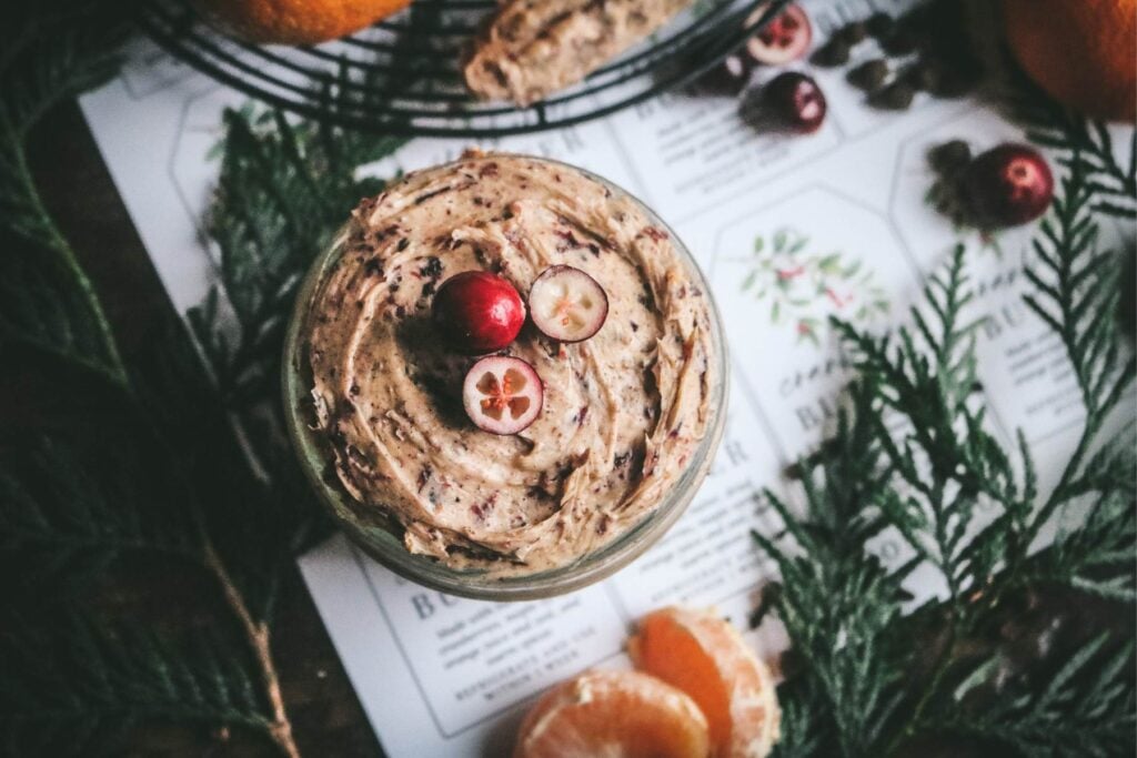 overhead view of a tan-colored cranberry compound butter with cinnamon, allspice, cloves, orange, and dried cranberries.