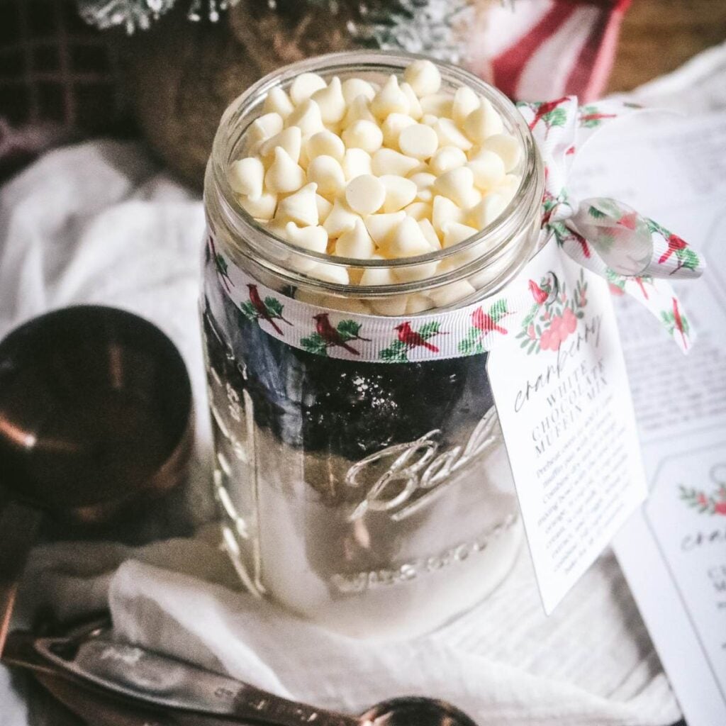 large glass jar with homemade muffin mix for holiday gifting with cranberries and white chocolate plus printable tags.