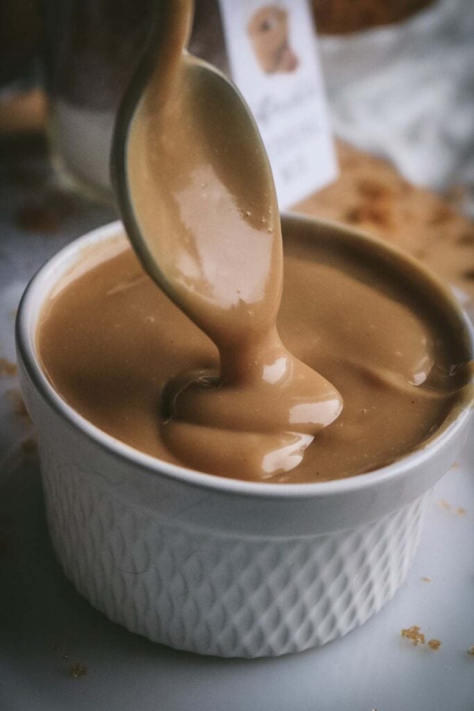 close up view of homemade butterscotch pudding being spooned into a ramekin.