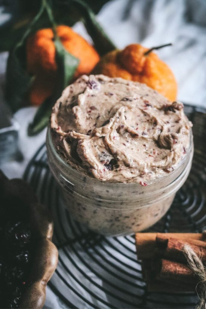 glass mason jar filled to the brim with a cinnamon and clove spiced cranberry maple butter for spreading on toast or dinner rolls.