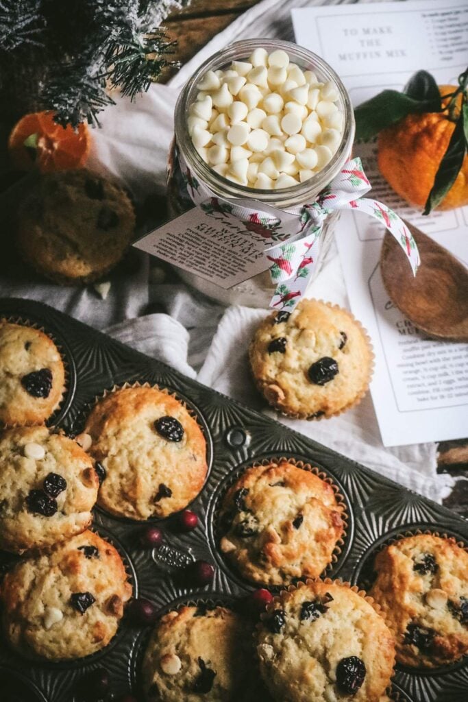 overhead view of a jar of homemade muffins in a jar plus freshly baked cranberry white chocolate muffins on a muffin pan.