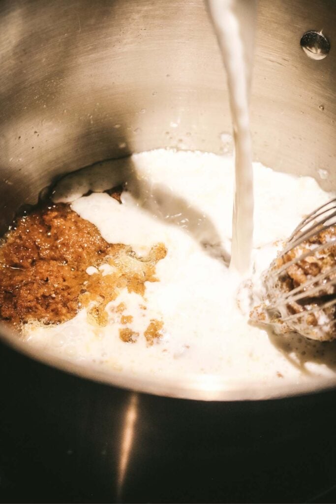 pouring whole milk into a pot to make homemade pudding.