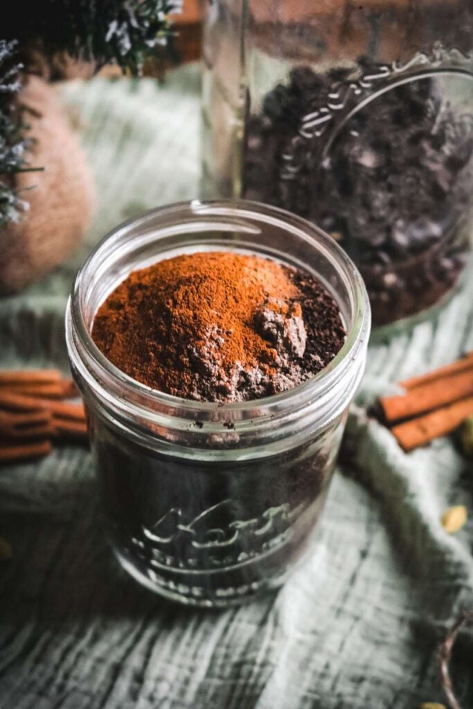 overhead view of a glass mason jar with coffee and spices with a jar of whole bean coffee in the background.