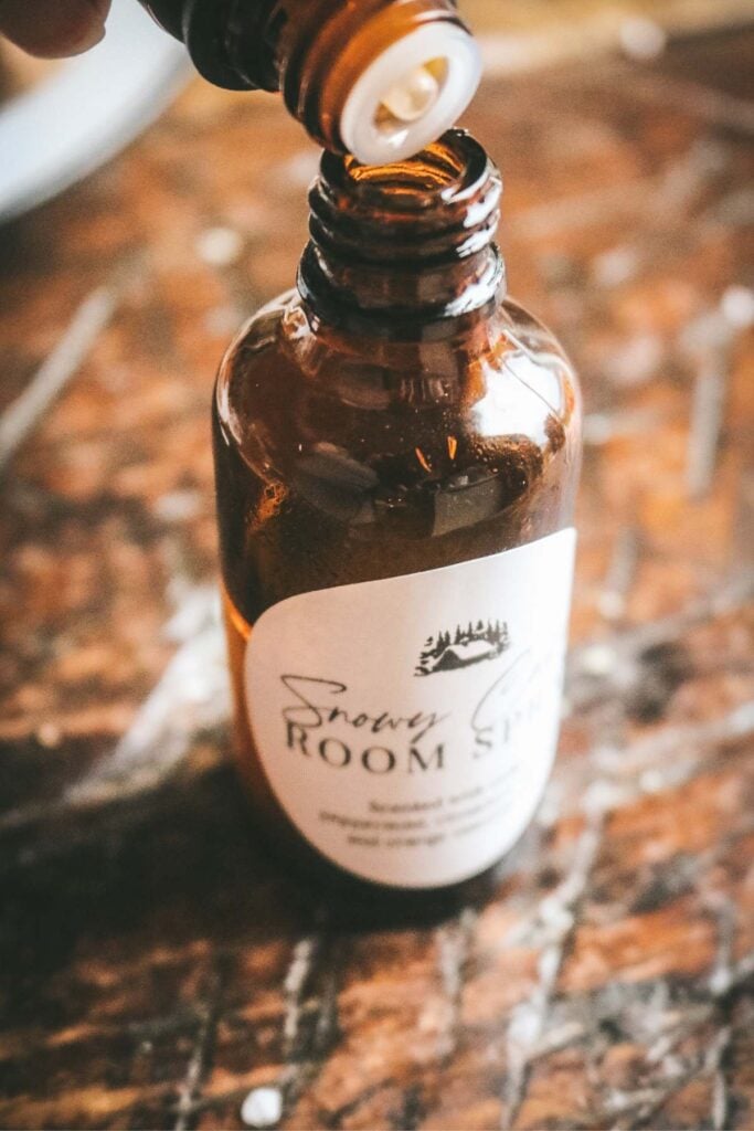 pouring essential oils into an amber glass spray bottle.
