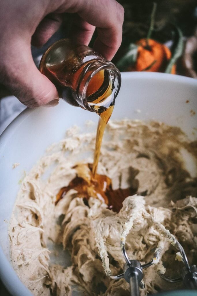 pouring maple syrup into a bowl to make spiced cranberry butter for christmas.