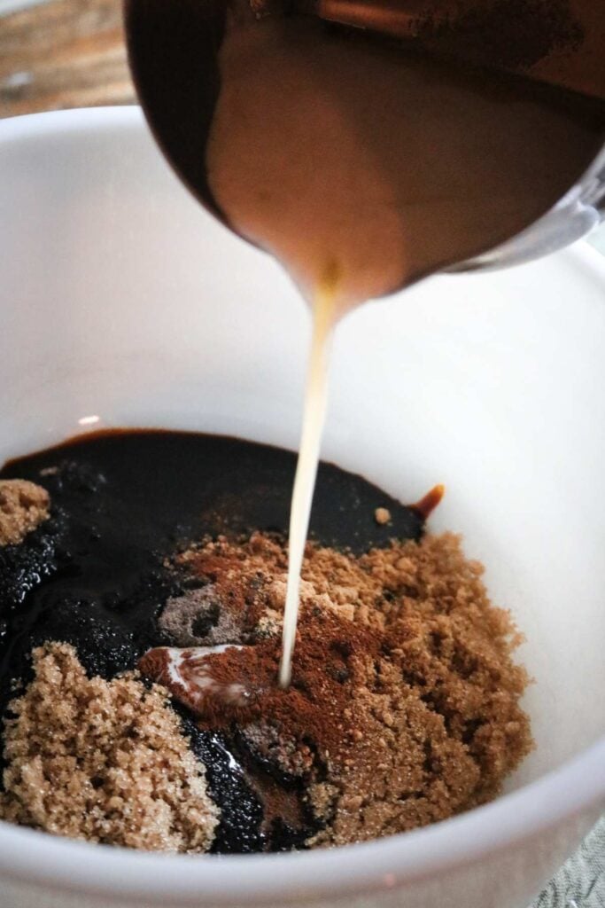 pouring melted butter into a mixing bowl with brown sugar, molasses, and spices.