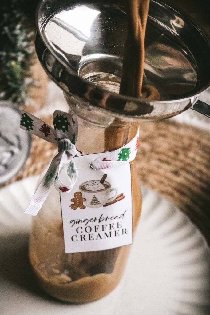 pouring homemade gingerbread coffee creamer into a glass bottle.