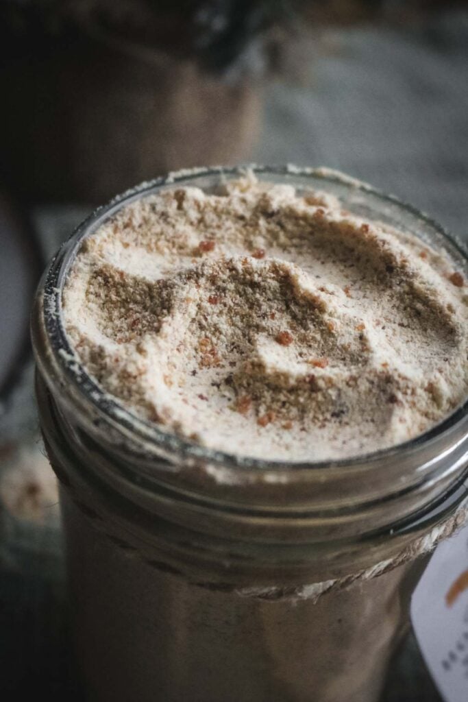 close up view of a jar of hot caramel mix with flecks of caramelized sugar.