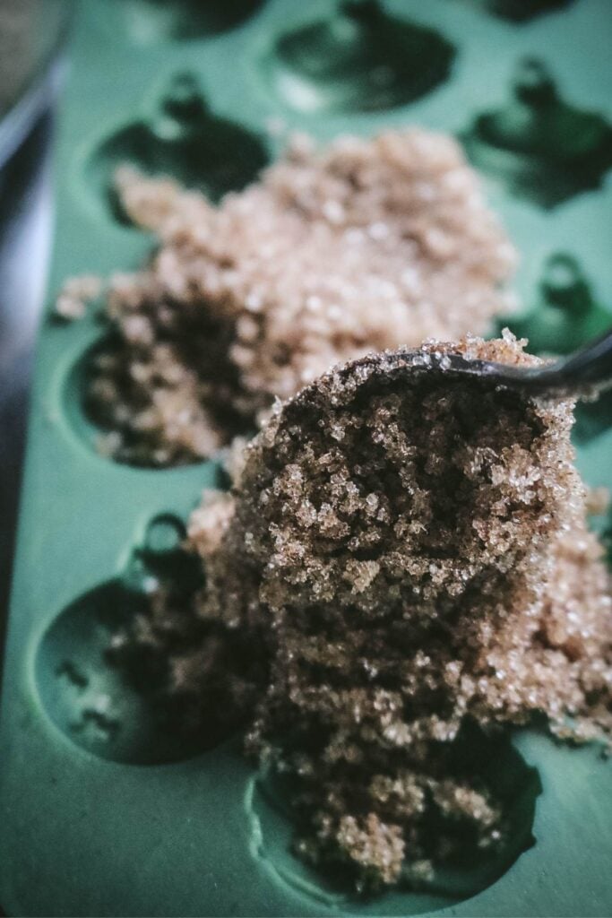 adding cinnamon sugar mixture to silicone mold for homemade snickerdoodle sugar cubes.