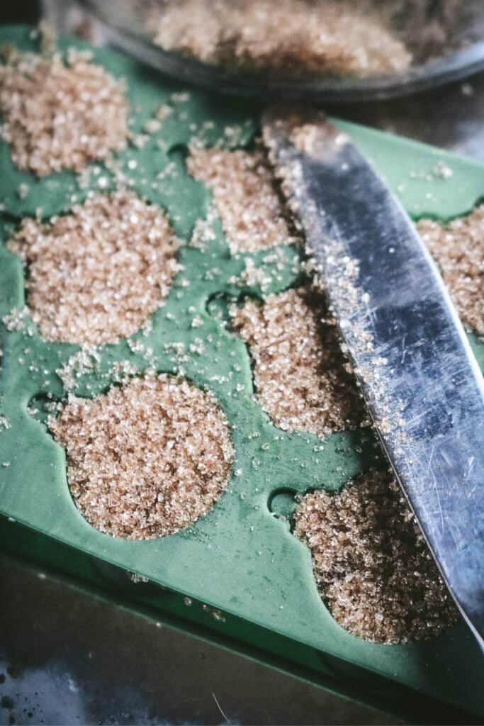 using a butter knife to level off silicone mold before dehydrating homemade christmas sugar cubes.