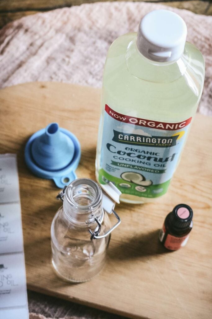 overhead view of ingredients and supplies to make homemade cutting board oil including fractionated coconut oil and essential oils.