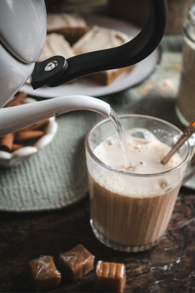 pouring hot water into a mug to make hot caramel milk from a dry mix.